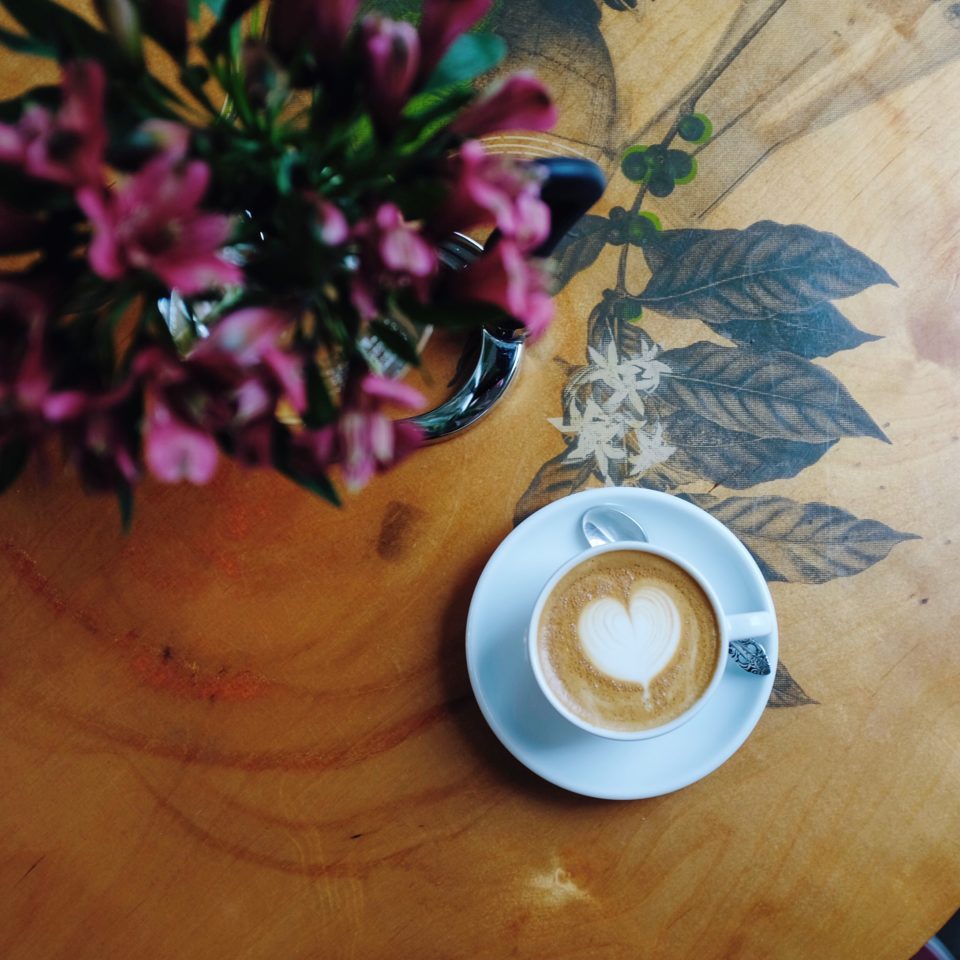 Coffee Cappuccino Sitting on a table with Flowers